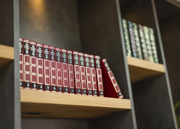 Vom Familienbetrieb zum echten Biohotel Reihe roter und grüner Lexikonbände in einem Bücherregal