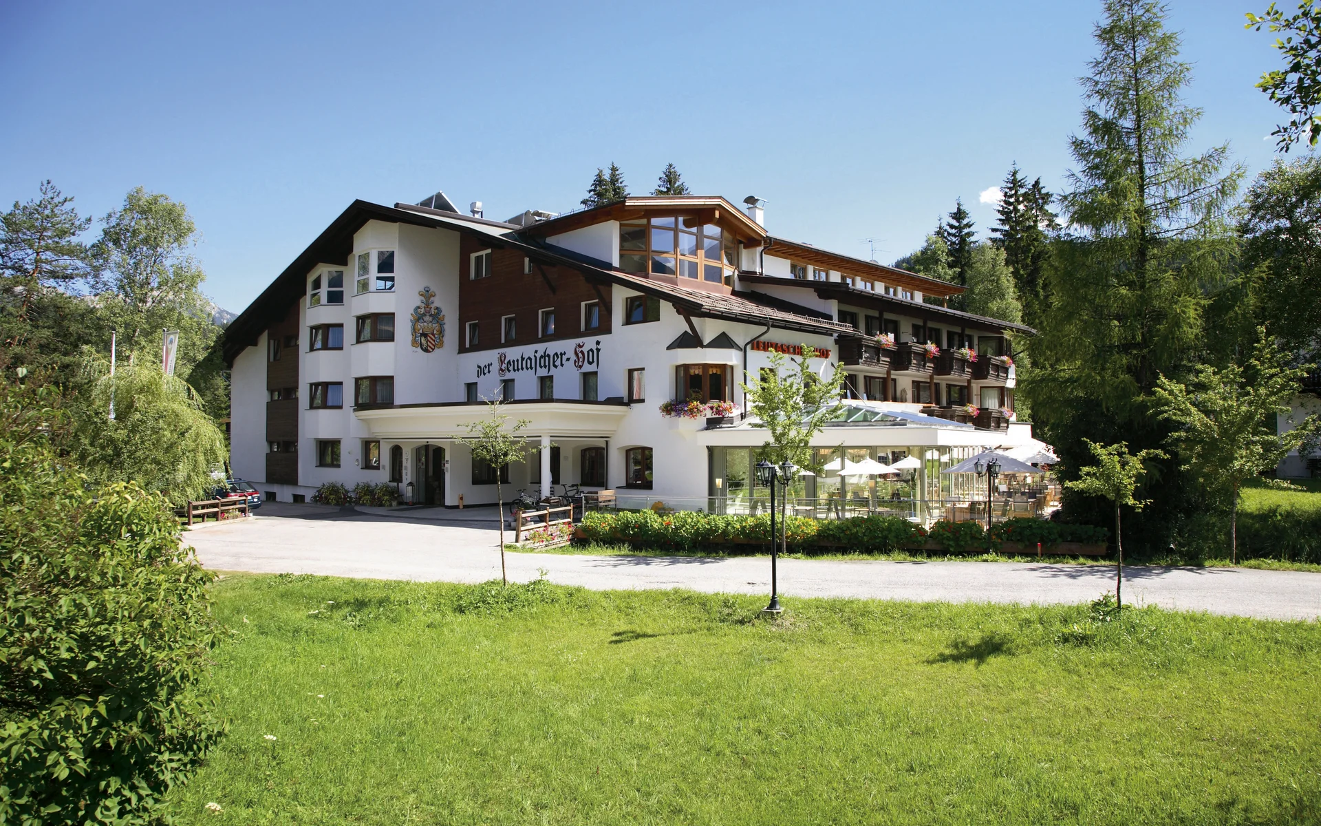 Werfen Sie einen Blick in die Bildergalerie Großes Hotelgebäude mit Terrasse und grüner Wiese im Vordergrund