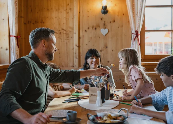 Ihre Almhütte in Tirol Familie sitzt am Tisch und malt gemeinsam in einem gemütlichen Raum