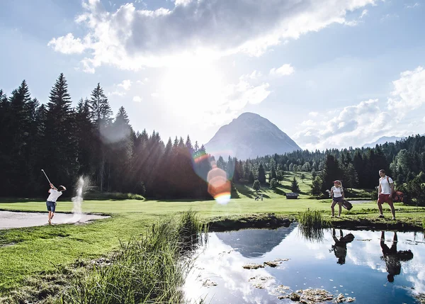 Sehenswürdigkeiten in Leutasch Person spielt Golf auf grünem Golfplatz mit Bergen und Wald im Hintergrund