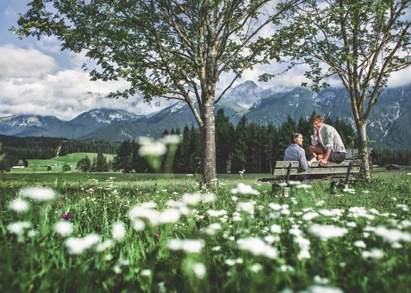 Sehenswürdigkeiten in Leutasch Zwei Personen sitzen auf einer Bank in blumiger Bergwiese mit Alpen im Hintergrund