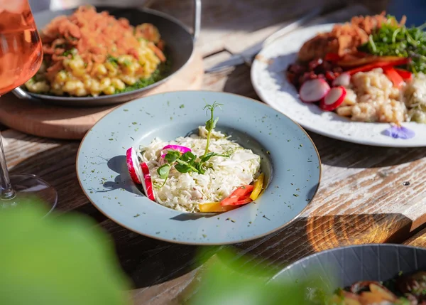 Ihre Almhütte in Tirol Bunte Salatgerichte und ein Glas Getränk auf einem Holztisch bei Sonnenschein