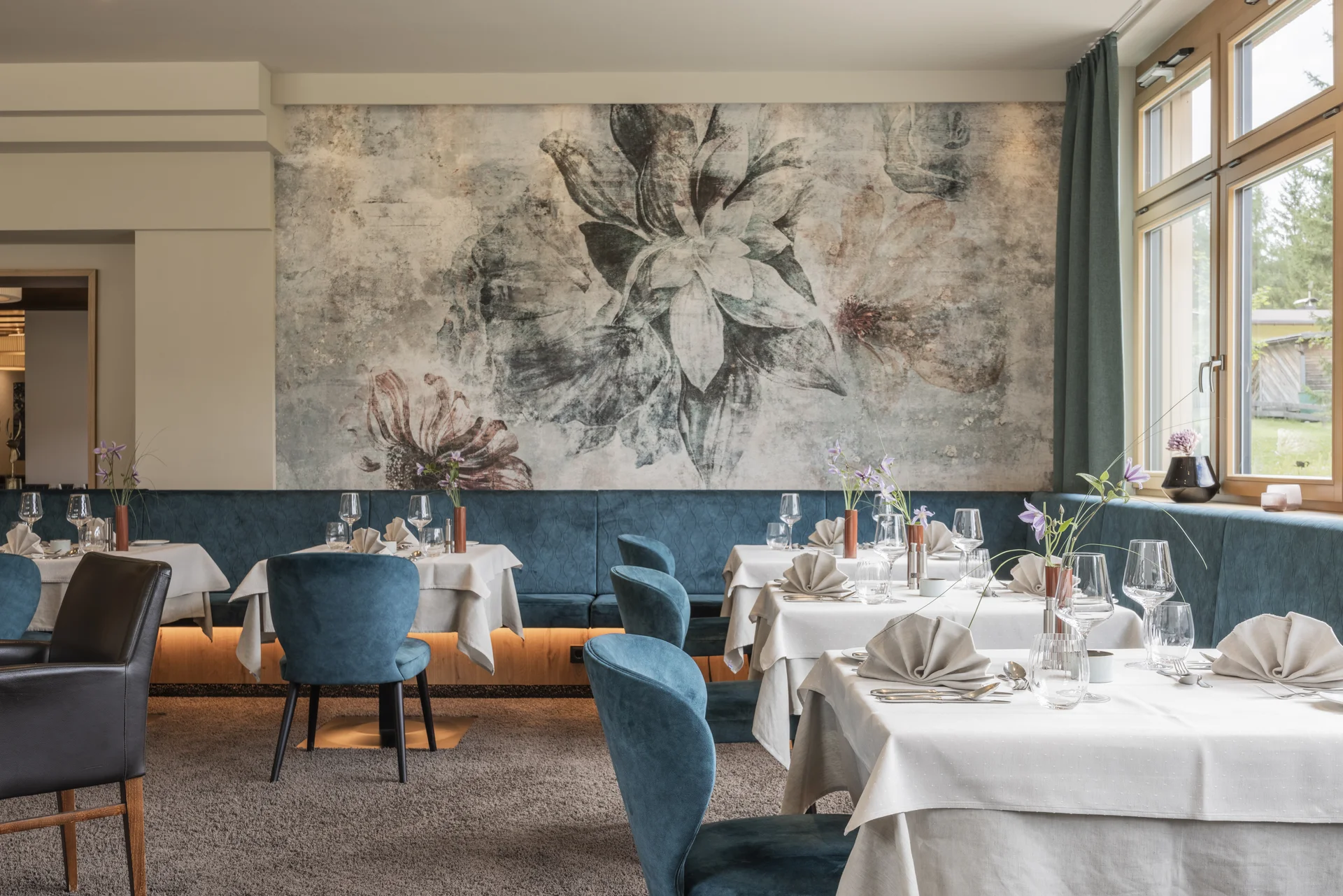 Genuss mit Haltung im Bio-Restaurant Elegantes Restaurant mit gedeckten Tischen und floralem Wandbild