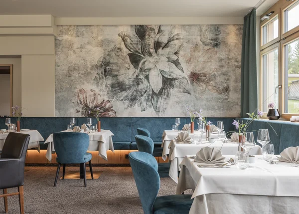 Vom Familienbetrieb zum echten Biohotel Elegantes Restaurant mit gedeckten Tischen und floralem Wandbild