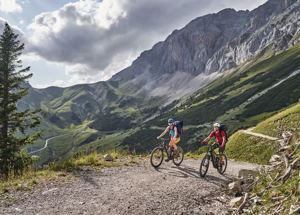 Vom Familienbetrieb zum echten Biohotel Zwei Radfahrer auf einem Bergweg mit Blick auf grüne Hügel und Felsen