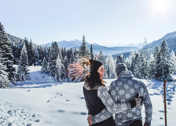 Wandertipps: Hier finden Sie die schönsten Touren! Paar umarmt sich in verschneiter Winterlandschaft vor Bergen