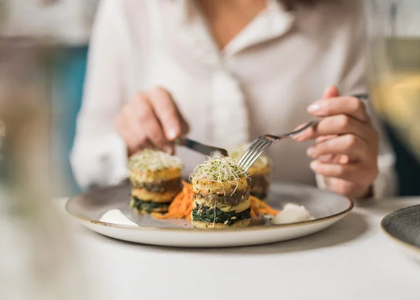 Vom Familienbetrieb zum echten Biohotel Person isst kunstvoll angerichtete vegane Speise mit Gabel und Messer