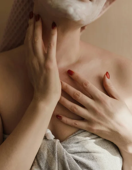 Entspannen im Hotel mit Sauna in Österreich Frau trägt Gesichtsmaske und hält Hand an Hals und Brust