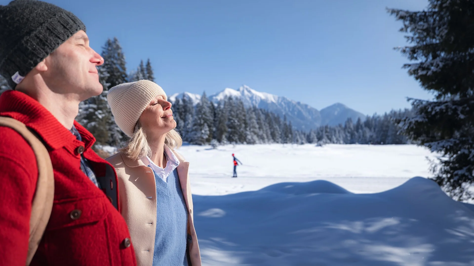 Wohlfühlprogramm oder Massage in Tirol? Paar genießt die Wintersonne in verschneiter Berglandschaft