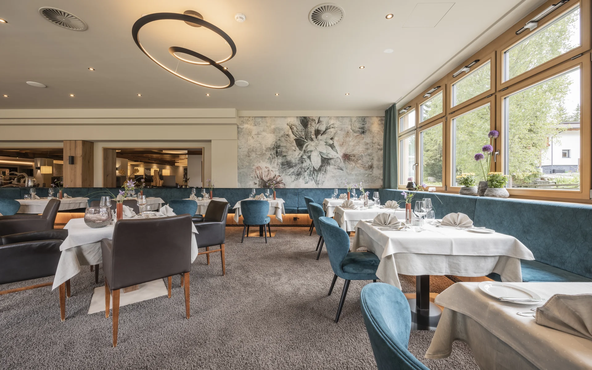 Werfen Sie einen Blick in die Bildergalerie Elegantes Restaurant mit weiß gedeckten Tischen und großen Fenstern