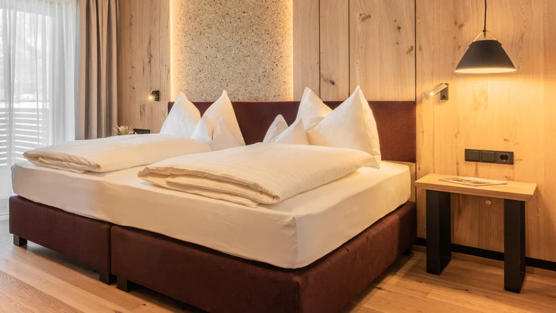 Urlaub in Leutasch Modernes Hotelzimmer mit Doppelbett, Holzwänden und Schreibtisch mit TV