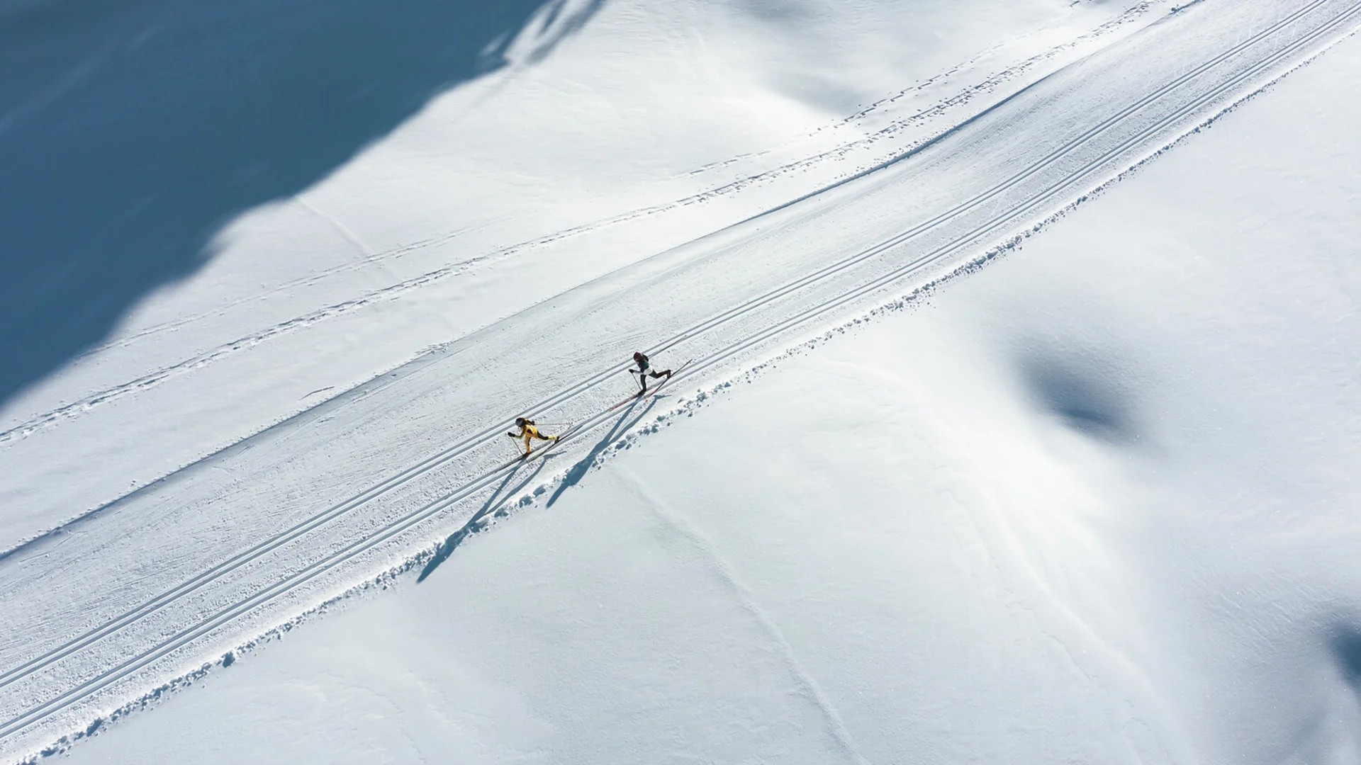 Urlaub in Bewegung: Ihr Aktivhotel in Tirol Zwei Langläufer auf einer verschneiten Loipe mit langen Schatten