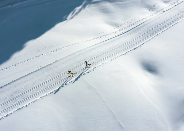 Urlaub auf Skiern: Ihr Langlaufhotel in Tirol Zwei Langläufer auf einer verschneiten Loipe mit langen Schatten