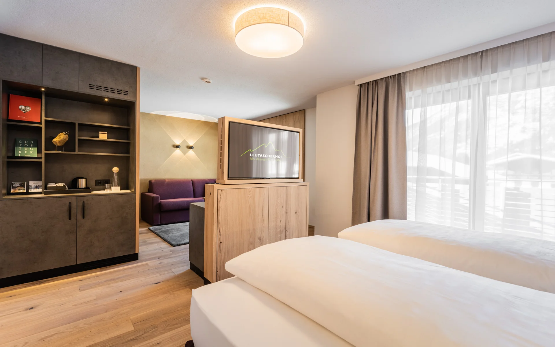Werfen Sie einen Blick in die Bildergalerie Modernes Hotelzimmer mit zwei Betten, TV und Blick auf den Vorraum mit Sofa