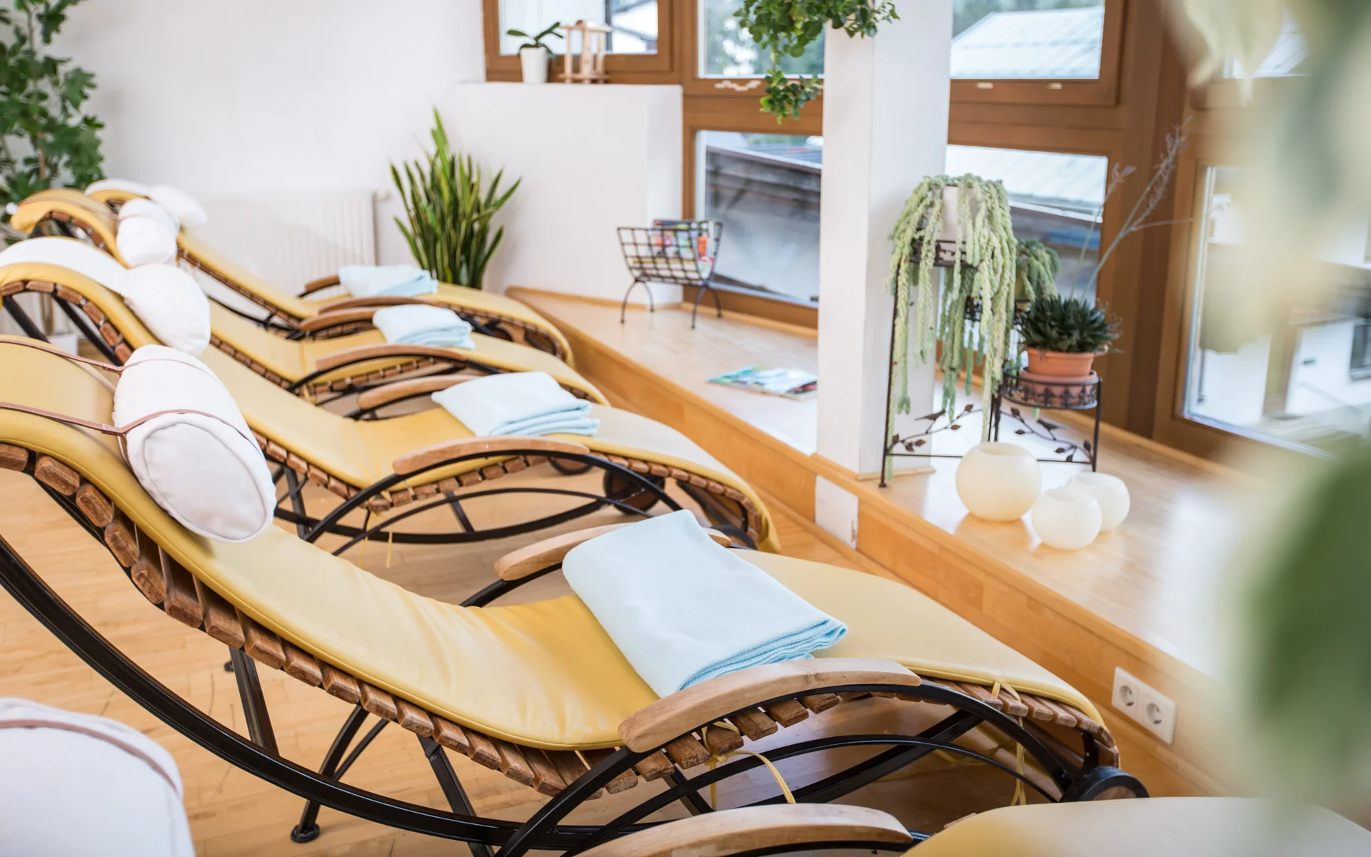 Werfen Sie einen Blick in die Bildergalerie Ruheliegen mit Kissen und Handtüchern in einem hellen, grünen Wellnessraum
