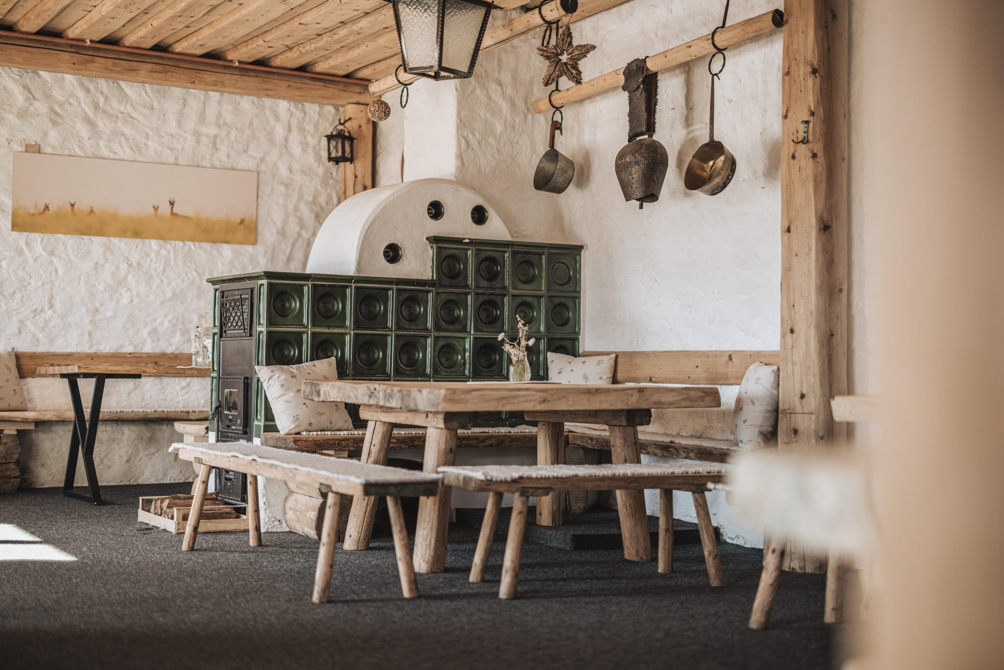 Ihre Almhütte in Tirol Gemütlicher Raum mit Holzmöbeln und traditionellem grünen Kachelofen