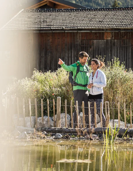 Der Bio-Blog des Leutascherhof Paar genießt Aussicht nahe Holzzaun und Teich vor Hütte in Natur