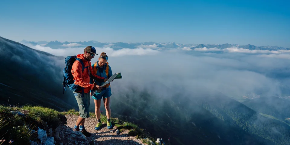Biohotel Leutascherhof – Ihr Kraftort in den Tiroler Alpen Zwei Wanderer mit Karte auf einem Bergweg über den Wolken