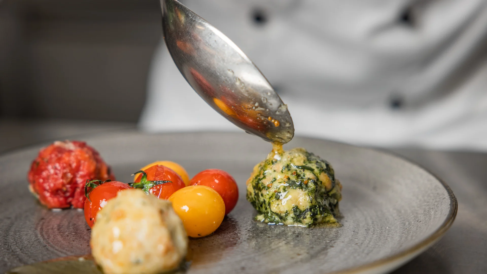 Biohotel Leutascherhof – Ihr Kraftort in den Tiroler Alpen Soße wird auf Spinatknödel und Tomaten auf einem Teller geträufelt